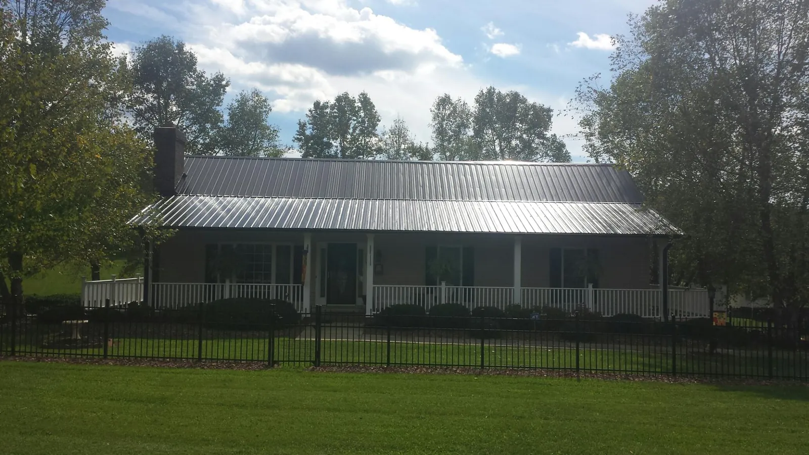 Gray metal roof on a brick ranch with a full width front porch — Gutter Guard Installation work by our crew in South Milwaukee