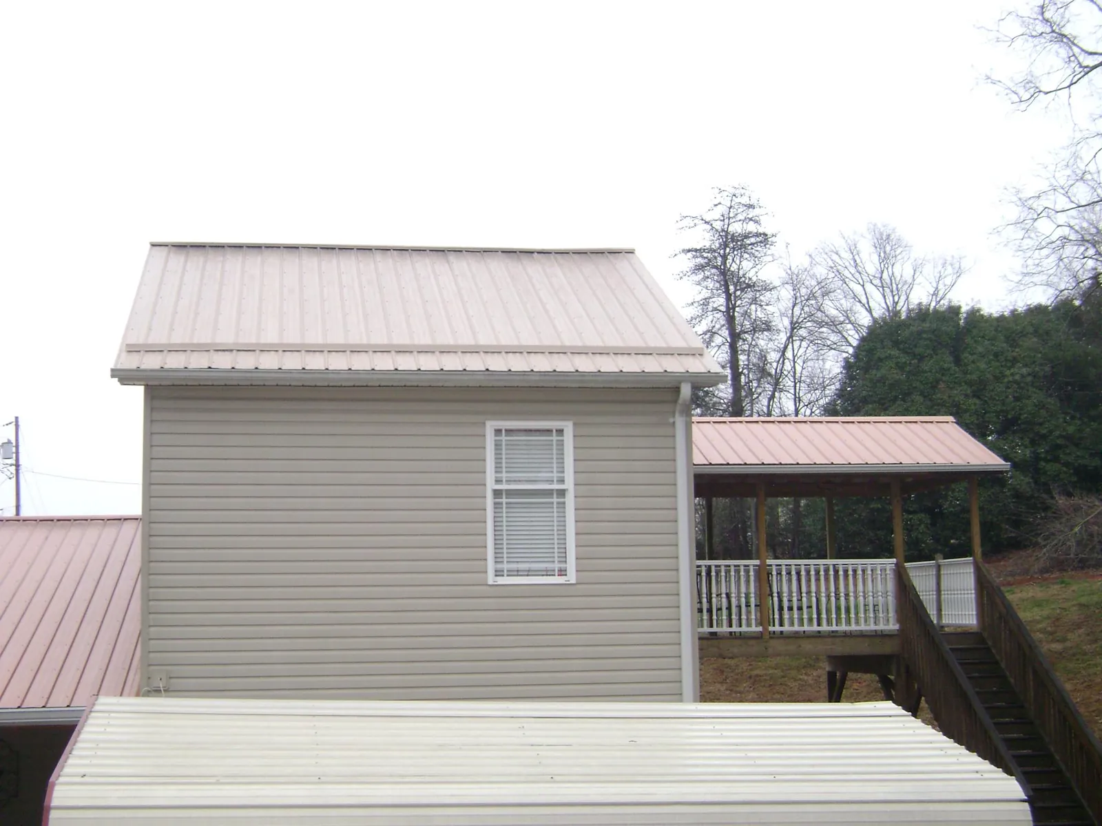 Tan metal roofs on a two story addition and attached porch, from a Roof Replacement job in South Milwaukee
