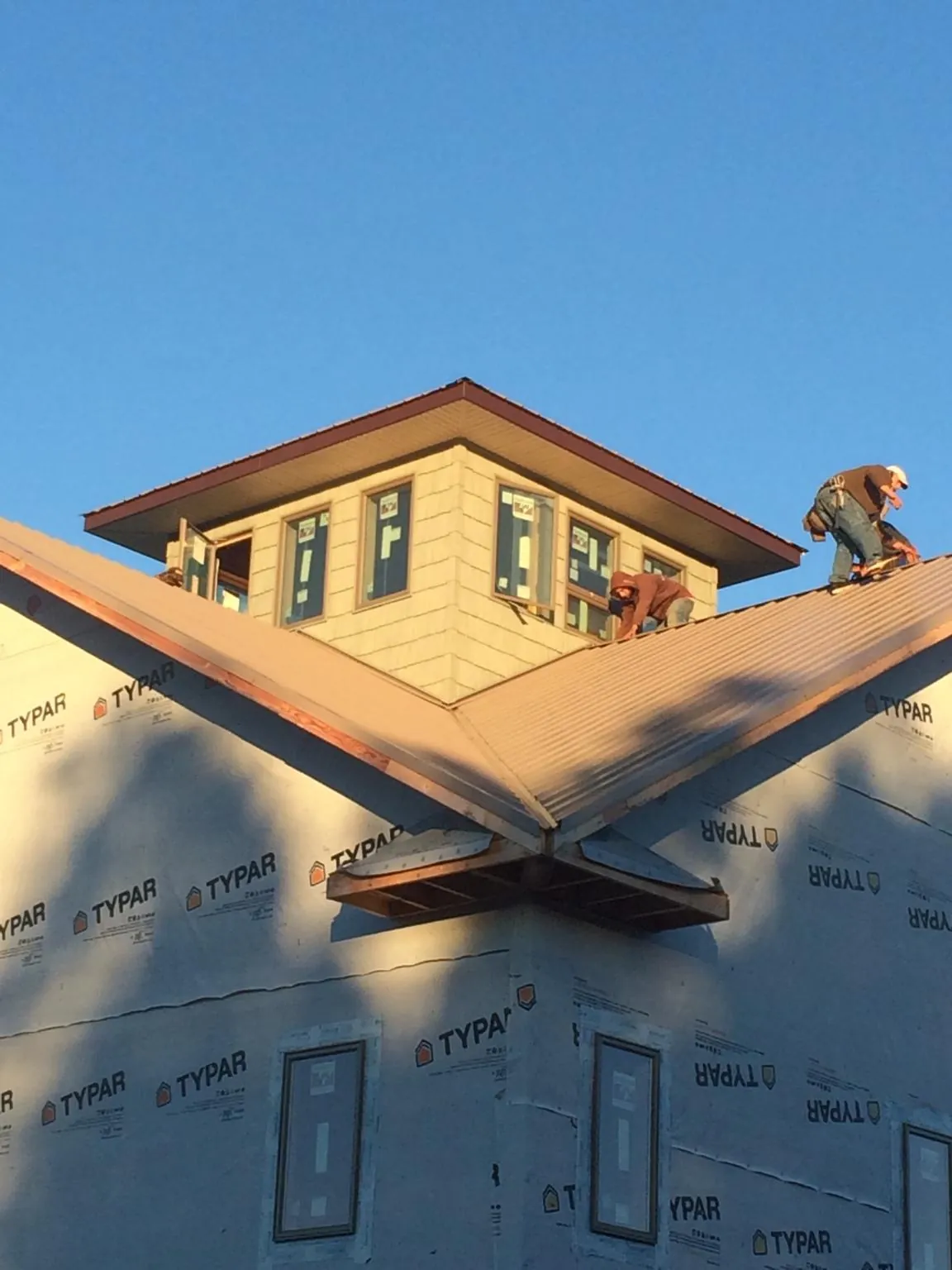 Roofers working around a rooftop cupola on a new metal roof at sunset — Roof Waterproofing in South Milwaukee by Roofing Brothers